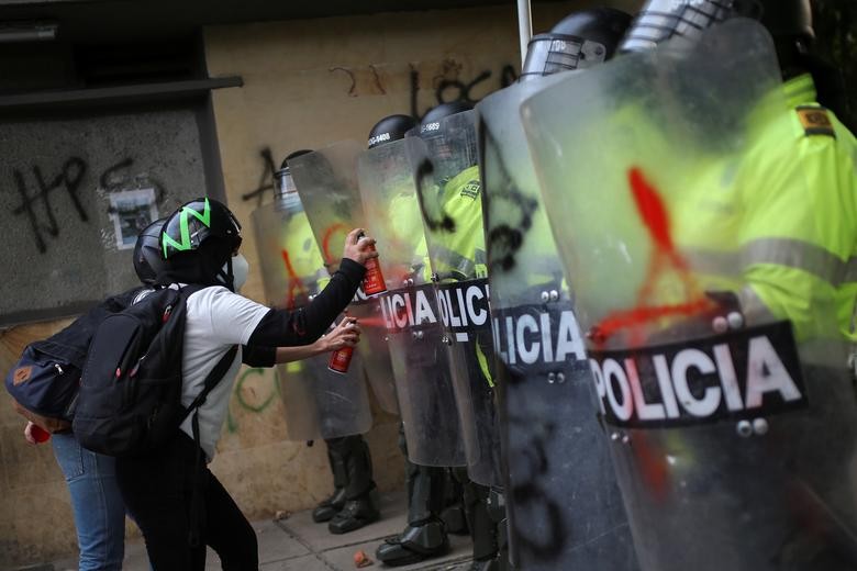 People spray paint on police riot shields as they protest outside a police station after a man, who was detained for violating social distancing rules, died from being repeatedly shocked with a stun gun by officers, according to authorities, in Bogota, Colombia September 10, 2020. REUTERS/Luisa Gonzalez